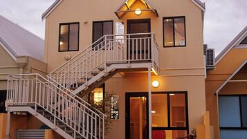 A two-story building with a balcony, a staircase, and a large window.