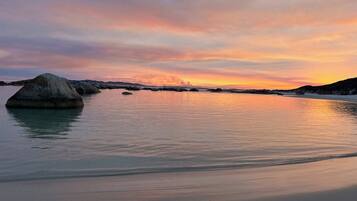 A beach with calm waters and large rocks.