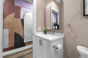 A bathroom with a white sink, a toilet, a mirror, and a towel rack.