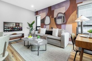 A modern living room with a sofa, coffee table, and a TV mounted on the wall.