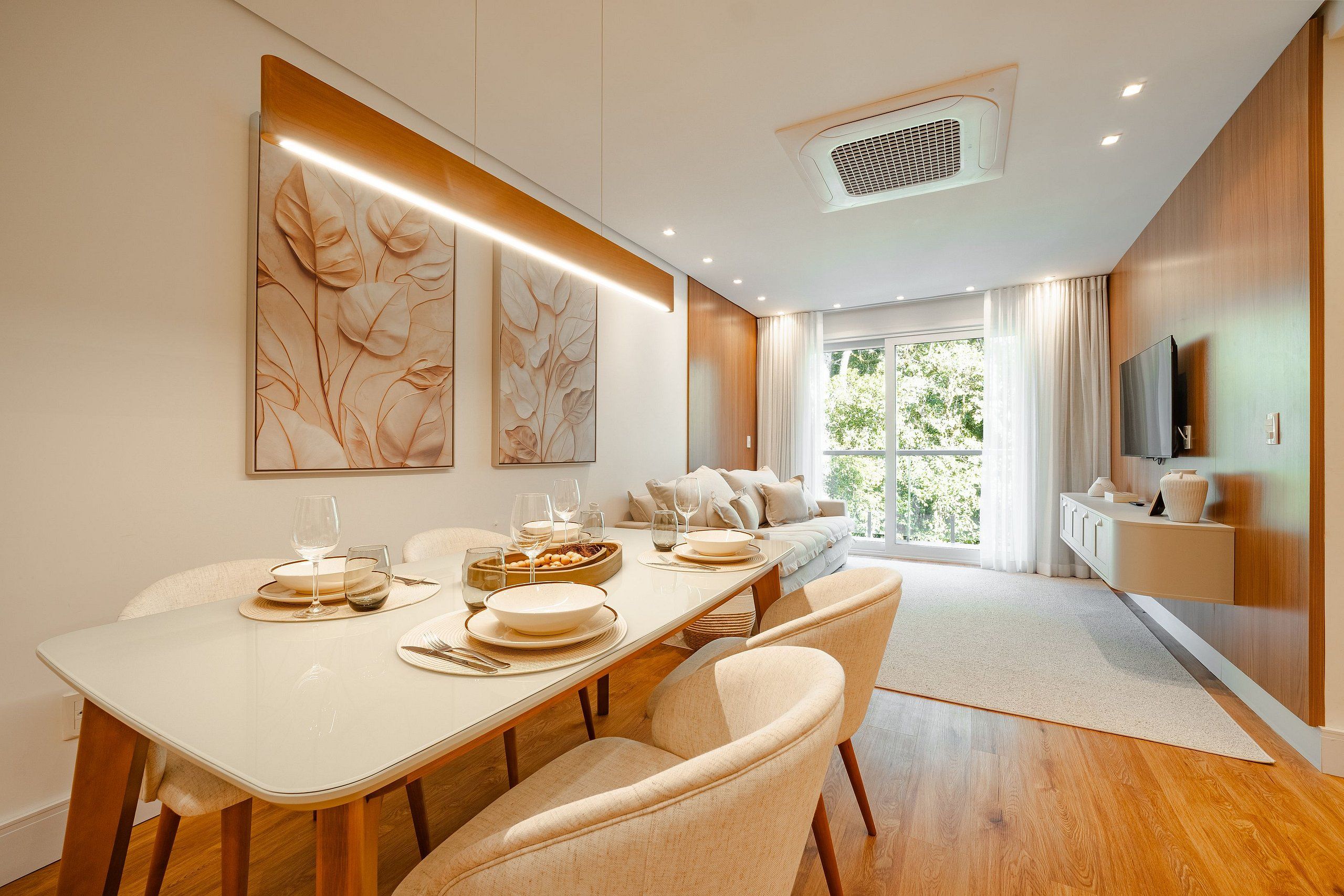 A modern dining area with a long table, chairs, and a view of the outdoors through large windows.