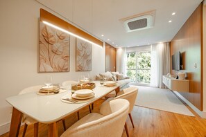 Un comedor moderno con una larga mesa, sillas y vistas al exterior a través de amplios ventanales.