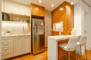 Une cuisine moderne dotée d’un réfrigérateur encastré, de meubles en bois, d’un plan de travail en granit et d’un coin bar avec deux tabourets.