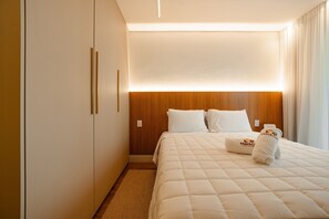 Une chambre d’hôtel avec un lit, une tête de lit en bois, du linge de lit blanc et une table de chevet.