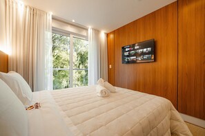 Una habitación de hotel con una cama grande, un televisor de pantalla plana en la pared y una ventana con cortinas.