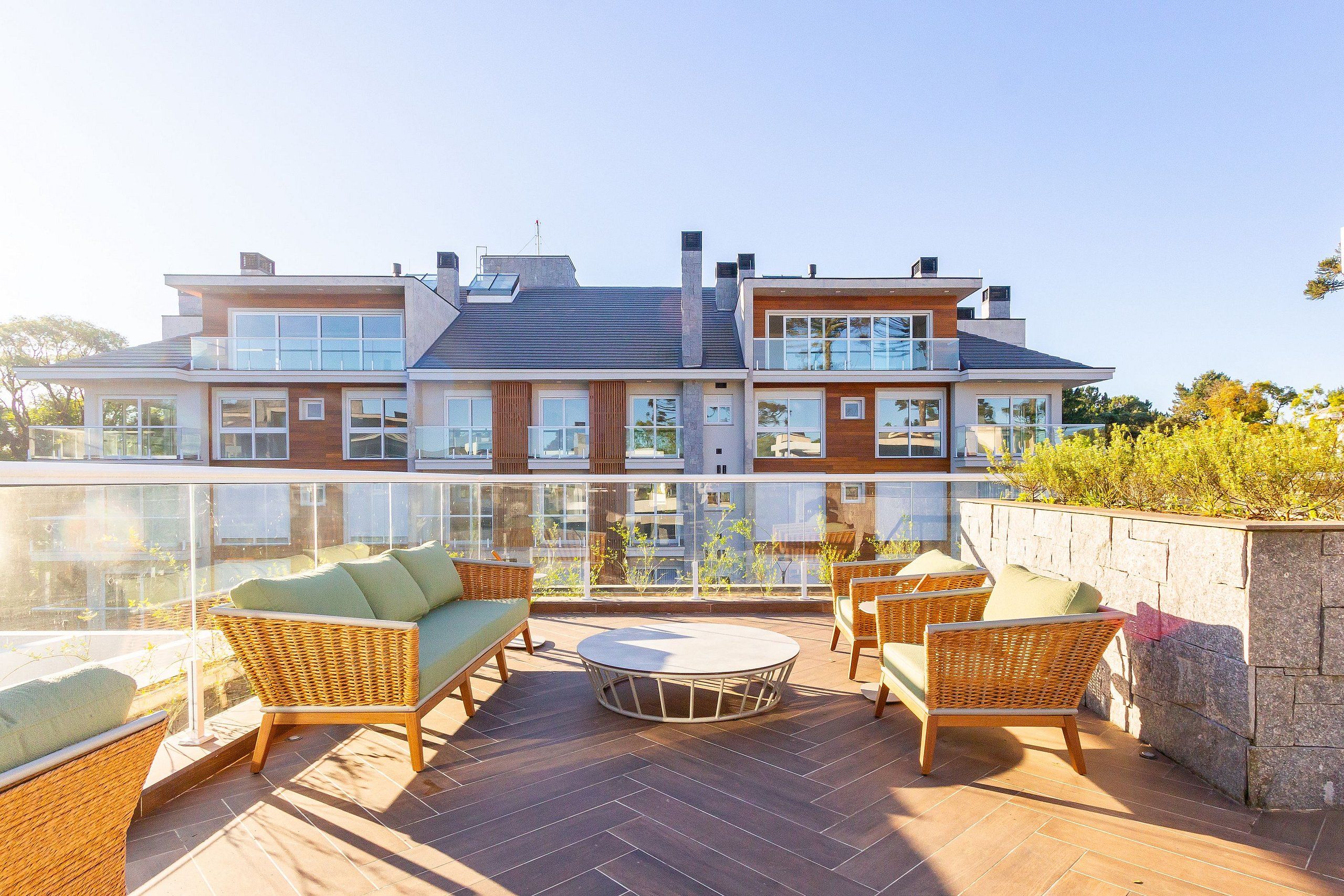 A modern two-story house with a balcony, furnished with wicker furniture and a round table.