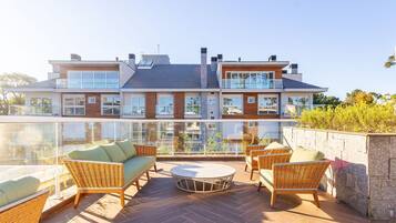 A modern two-story house with a balcony, furnished with wicker furniture and a round table.