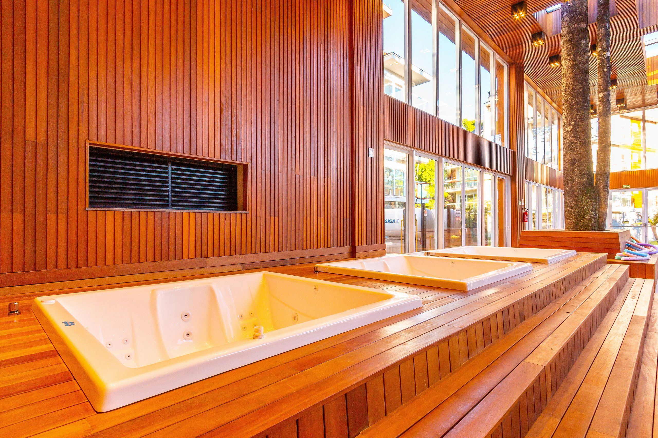 A spa area with wooden paneling and two large tubs.