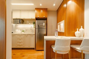 Una cocina moderna con armarios de madera, un refrigerador de acero inoxidable y una zona de bar con dos sillas.