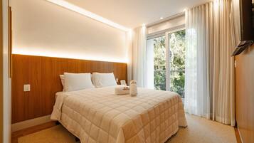 A hotel room with a large bed, a wooden headboard, a flat-screen TV, and a window with curtains.