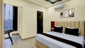 Ein modernes Hotelzimmer mit einem großen Bett, einem Schreibtisch und einem Fenster mit Jalousien.