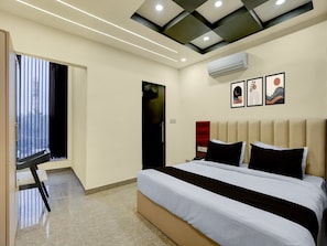 Ein modernes Hotelzimmer mit einem großen Bett, einem Schreibtisch und einem Fenster mit Jalousien.