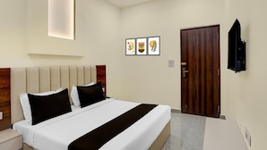 Ein modernes Hotelzimmer mit einem Bett, Nachttischen, einer Holztür und gerahmten Kunstwerken an der Wand.