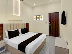Ein modernes Hotelzimmer mit einem Bett, Nachttischen, einer Holztür und gerahmten Kunstwerken an der Wand.
