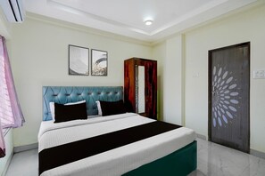 A bedroom with a tufted headboard, a bed with white and black bedding, and two abstract wall art pieces. - Hotel O Ring Road Nagpur (Nagpur)