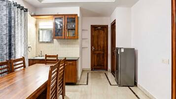 A modern kitchen with a dining area, wooden cabinets, and a refrigerator.