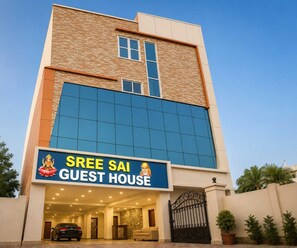 En bygning med et skilt, der viser 'SREE SAI GUEST HOUSE', og en portindgang.