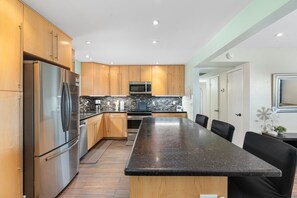 Eine moderne Küche mit einem Edelstahl-Kühlschrank, einer Mikrowelle und einer großen Kochinsel mit Sitzgelegenheiten.