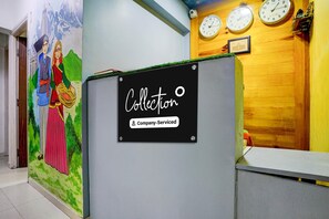 Ein Empfangsbereich mit Wandgemälde, einem Schild mit der Aufschrift 'Collection Company-Serviced' und drei Uhren an der Wand.