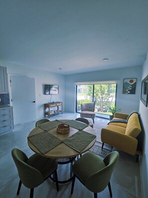 A dining area with a round table, four chairs, and a sofa. - Modern & Sleek 1-bedroom apartment (Homestead)
