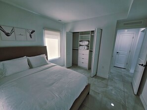 Ein Schlafzimmer mit einem Bett, einem Kleiderschrank und einer Tür zu einem anderen Raum.