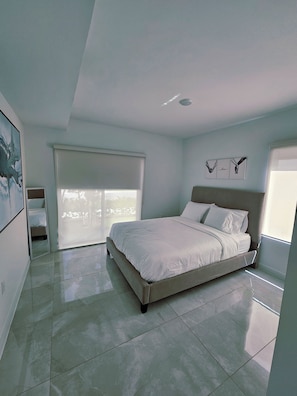 A bedroom with a bed, a window, and a door. - Modern & Sleek 1-bedroom apartment (Homestead)