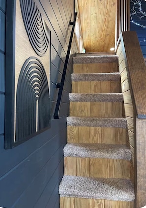 A wooden staircase with a handrail and carpeted steps.