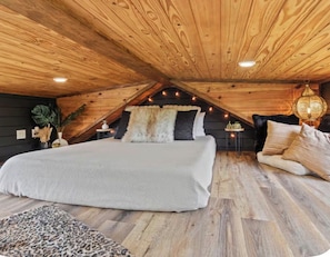A bedroom with a large bed, wooden ceiling, and a decorative lantern.