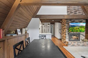 A dining area with a long table, chairs, and a bookshelf with books and decorative items. - Lakefront Escape | Hot Tub, Theater & Game Room (Monticello)