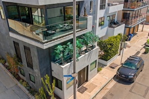 A modern multi-story building with balconies, large windows, and outdoor planters. - MB Highland - Cute Apartment Steps To Beach (Manhattan Beach)