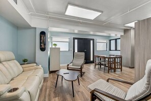 Ein modernes Wohnzimmer mit einer Couch, Sesseln, einem Couchtisch und einem Essbereich mit Tisch und Stühlen.