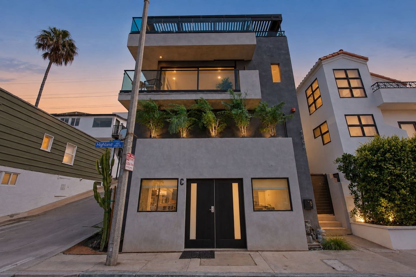 A modern multi-story building with a flat roof, large windows, and a balcony.