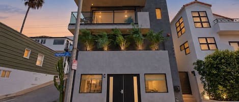A modern multi-story building with a flat roof, large windows, and a balcony.
