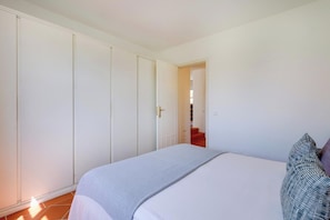 A bedroom with a bed, a wardrobe, and a door leading to a staircase. - Casa da Galé | Pool & Terrace (Albufeira)