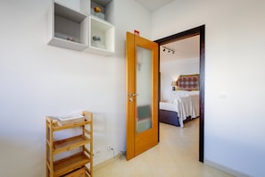 Quarto com cama, mesa de cabeceira, criado-mudo e guarda-roupa.