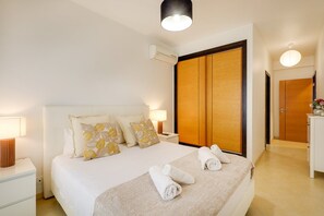 Ein Hotelzimmer mit Bett, Nachttischen, einem Kleiderschrank und einer Badezimmertür.