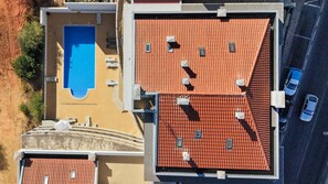 Vista aérea de uma propriedade com piscina, várias varandas e área de estacionamento.