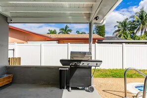 An outdoor patio with a barbecue grill, a trash can, and a poolside area. - CL6900-3D-Private Heated pool home in a quiet area (Fort Lauderdale)