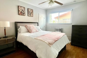 A bedroom with a bed, a nightstand, a dresser, a ceiling fan, and a window with a view. - CL6900-3D-Private Heated pool home in a quiet area (Fort Lauderdale)