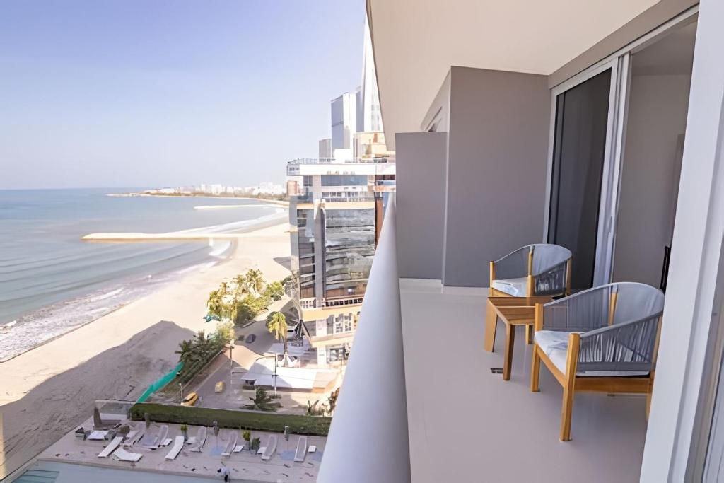 A balcony with a view of a beach and a modern building.