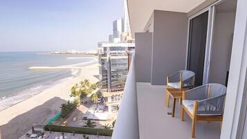 A balcony with a view of a beach and a modern building.