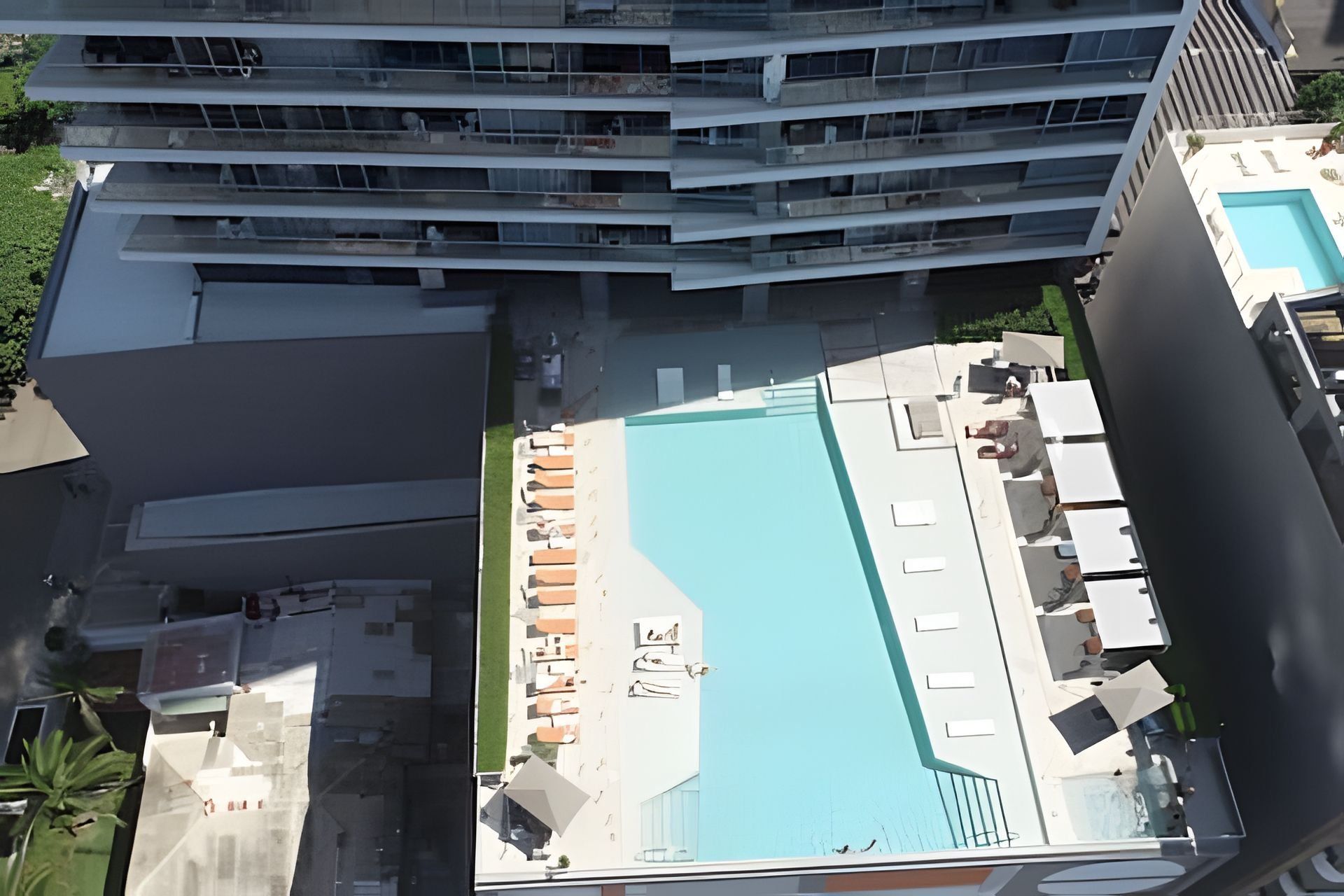 Una piscina en la azotea con vistas a un edificio de gran altura al fondo.