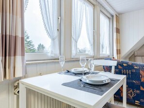 A dining area with a table set for two, two wine glasses, a plate, and cutlery. - Holiday Apartment 1 (St. Peter-Ording)
