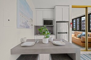 Eine moderne Küche mit weißen Schränken, einem Edelstahlkühlschrank und einer Mikrowelle.