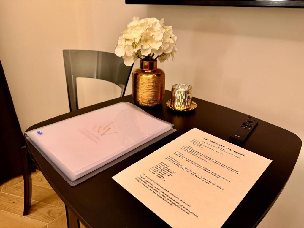 A table with a laptop, a menu, and a vase with flowers.
