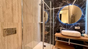 Un bagno moderno con cabina doccia in vetro, parete in marmo e mobile lavabo.