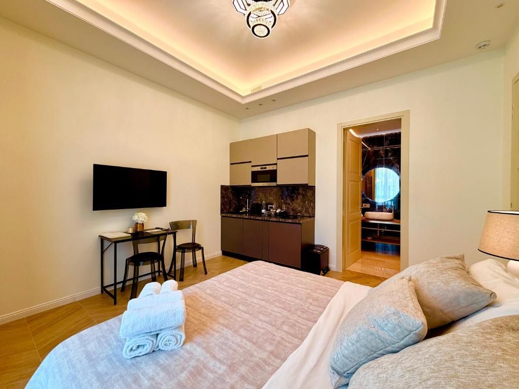 A hotel room with a bed, a desk, a television, and a kitchenette.