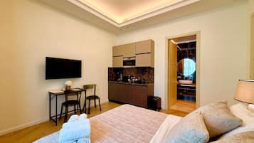 A hotel room with a bed, a desk, a television, and a kitchenette.