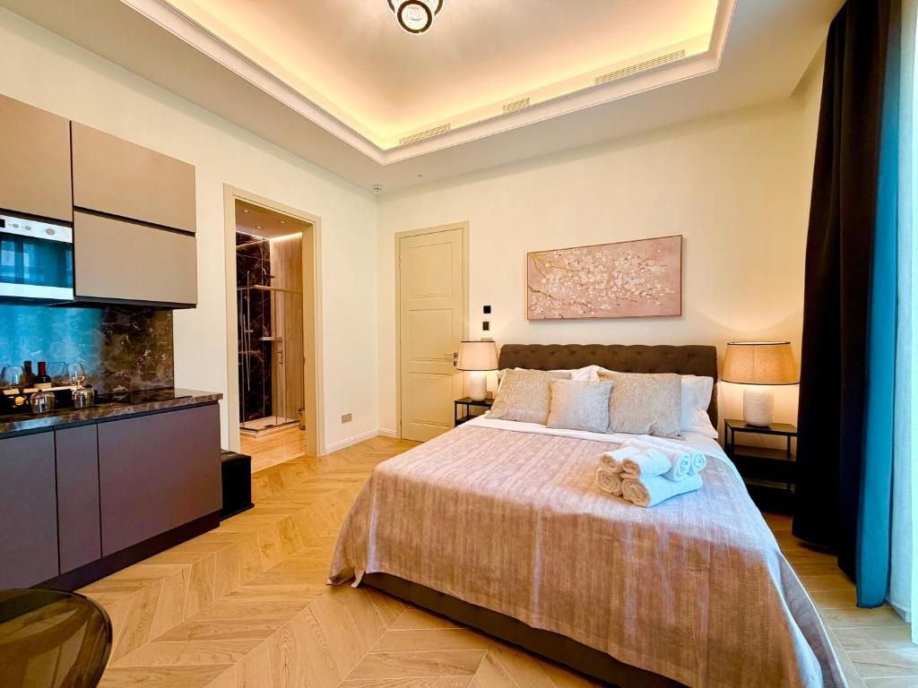 Quarto de hotel com cama, abajures, um quadro e vista para o exterior.
