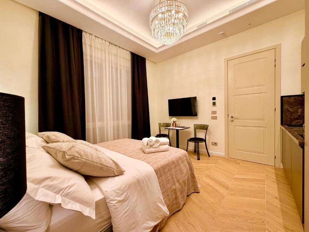 Habitación de hotel con una cama, un televisor, un escritorio con sillas y una puerta.